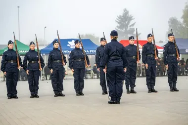 Funkcjonariusze Straży Granicznej w granatowych mundurach z karabinami stoją w szeregu na placu podczas uroczystej zbiórki.
