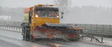 Pług śnieżny odśnieża drogę podczas intensywnego opadu śniegu.